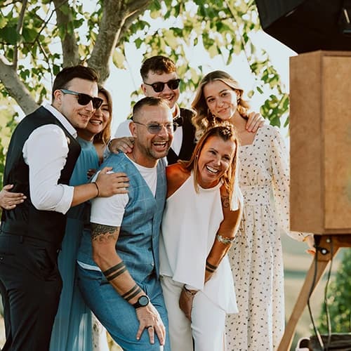 Gäste lachen und posieren gemeinsam vor einer Vintage-Fotobox auf einer Hochzeit in der Steiermark