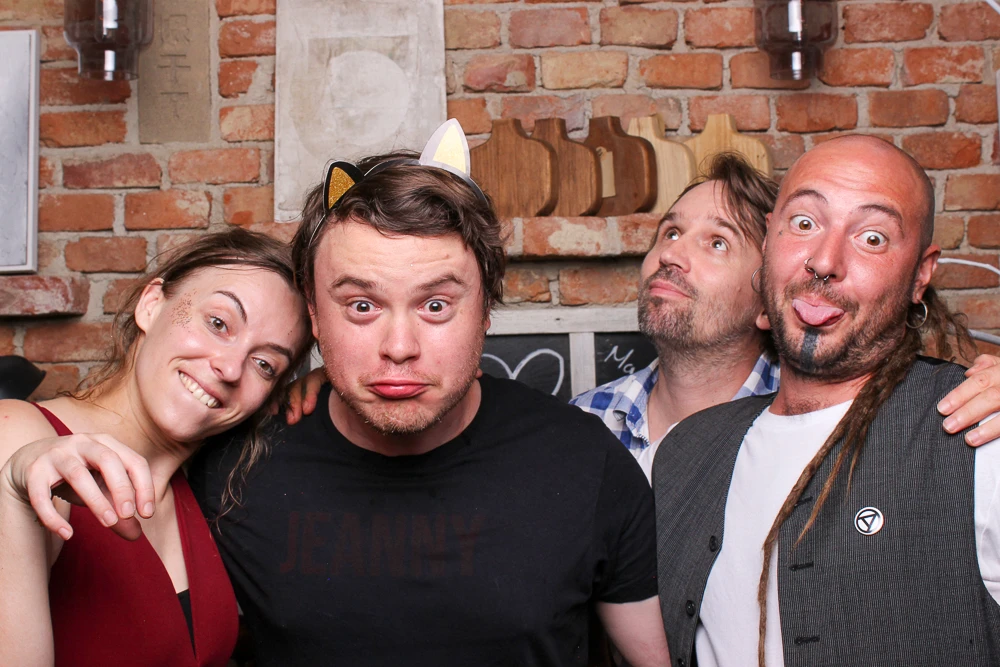Eine Gruppe von vier Freunden macht alberne Gesichter in der Fotobox und genießt den Spaß.