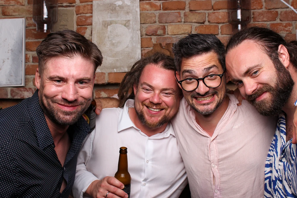 Eine Gruppe von sechs Männern posiert spaßig in der Fotobox bei einem ausgelassenen Event.