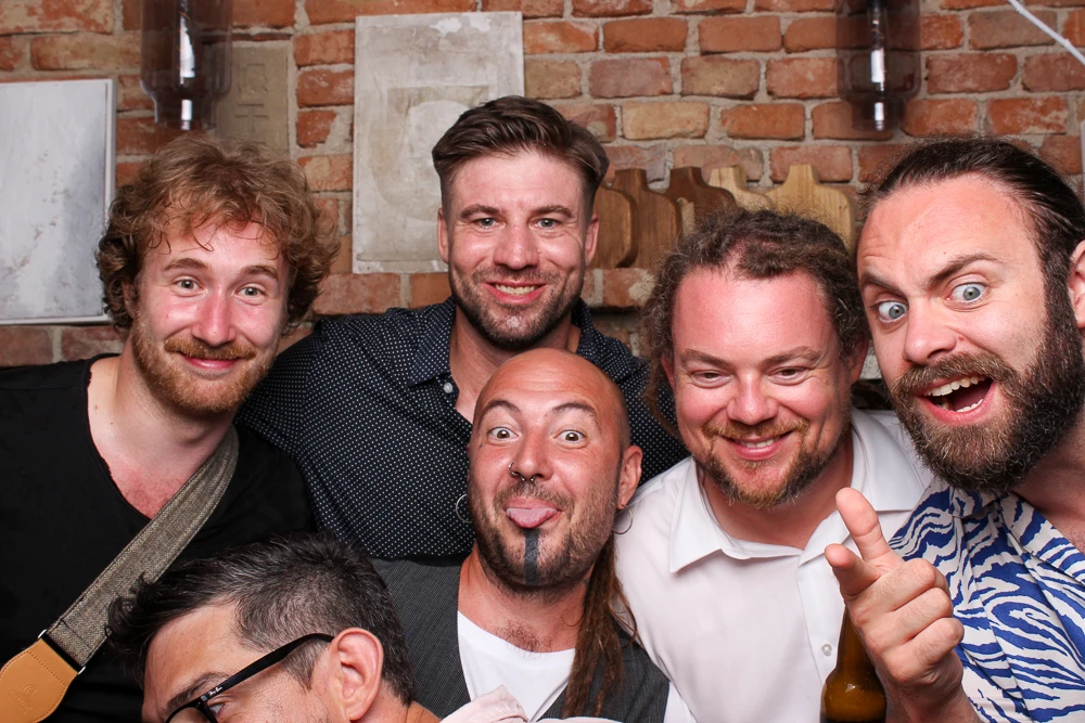 Fünf Freunde stehen vor einer Fotobox und haben Spaß.